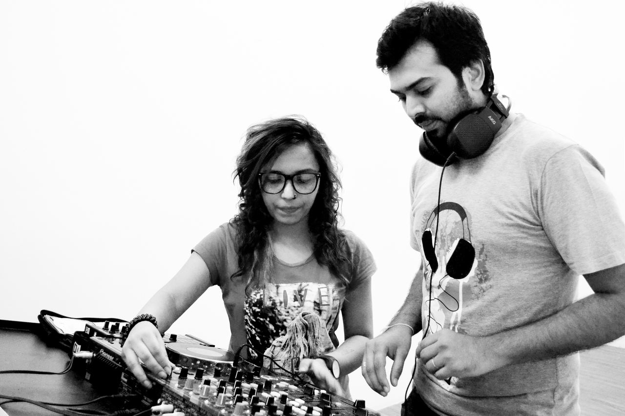 Black and white photo of a faculty member guiding a student on a DJ mixer