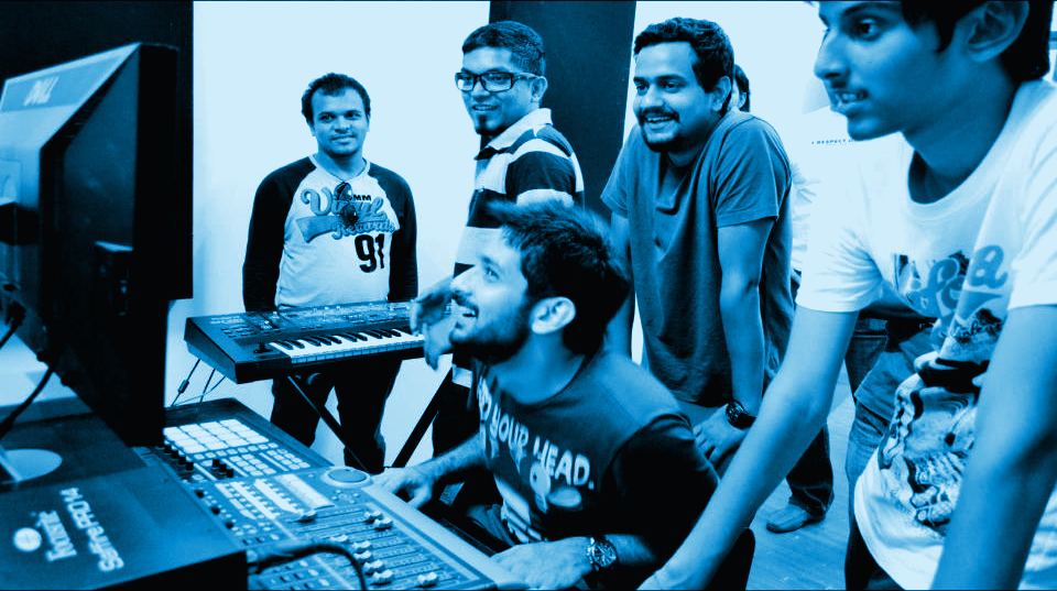 Students crowding around a mixer and synth at the Mega Masterclass